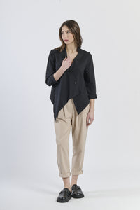 Outfit con camicia nero asimmetrica e pantaloni beige chiari, scarpe mocassini scure