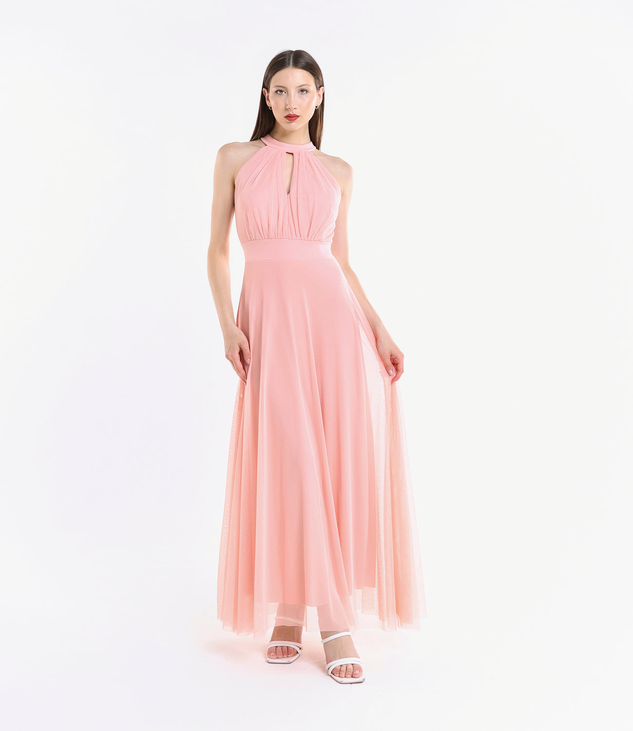 Donna con abito lungo rosa, colletto a nodo, pianta verde tropicale accanto