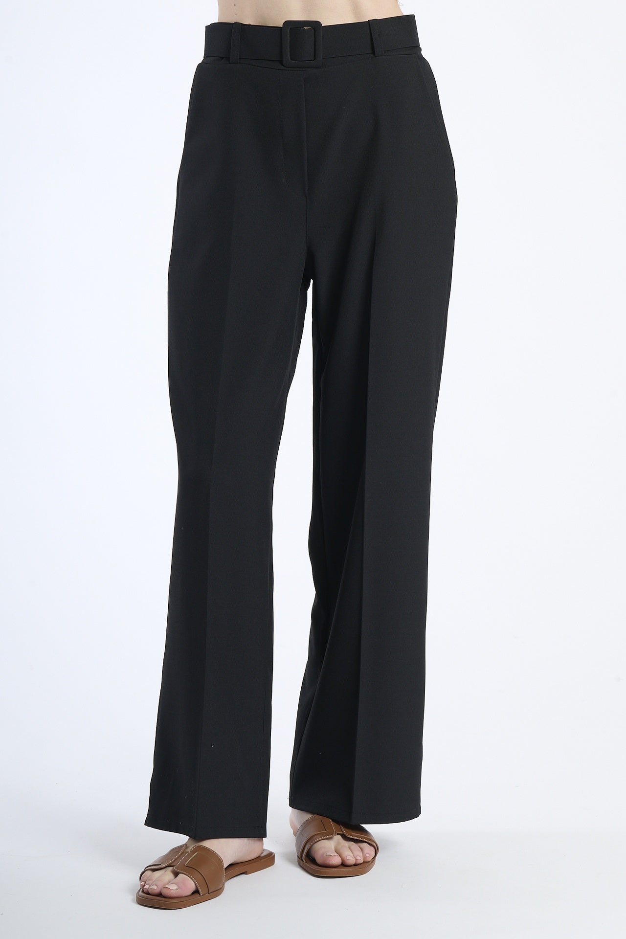 Pantaloni larghi neri con cintura, taglio a zampa, abbinati a sandali.