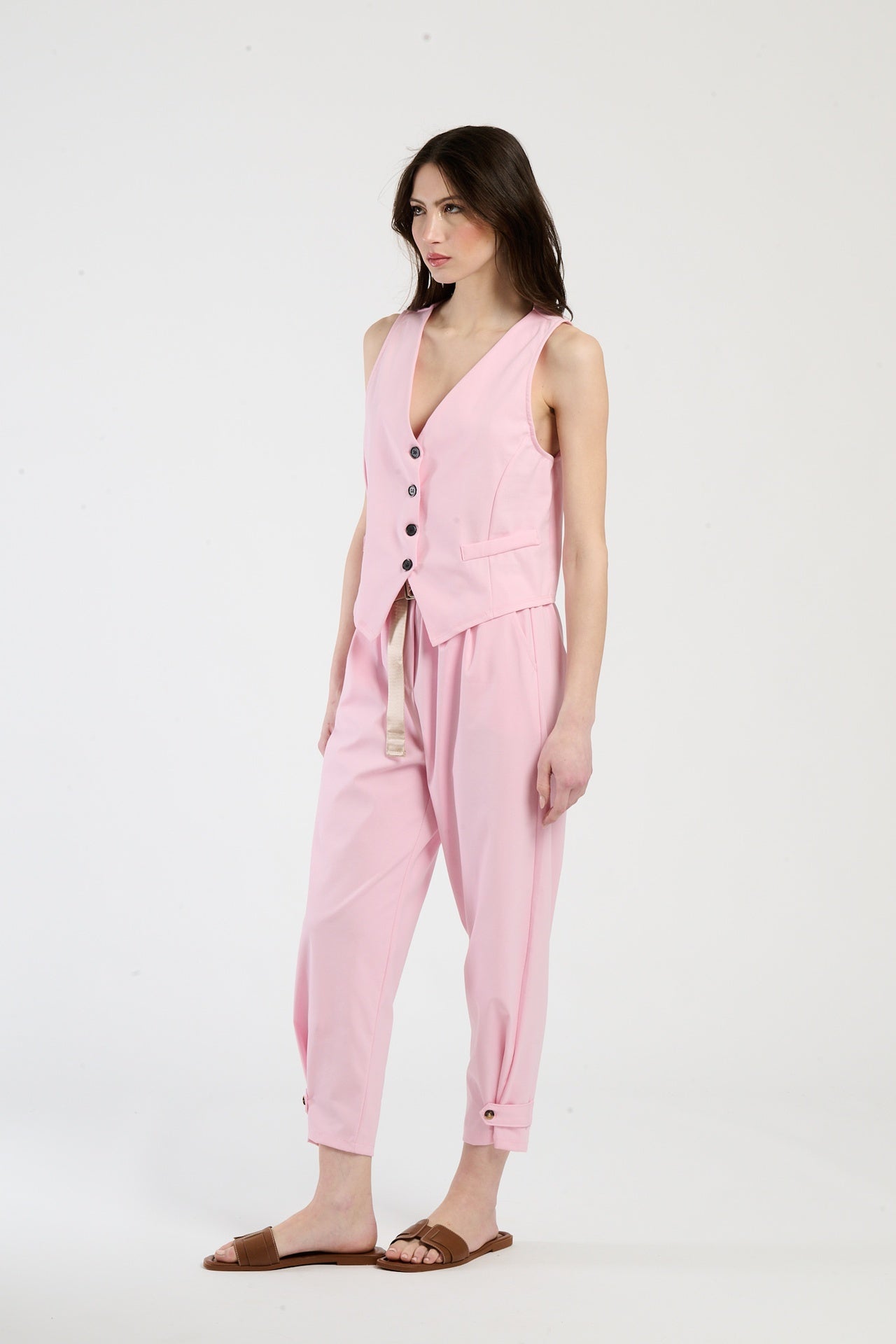 Modella indossa completo rosa: gilet senza maniche e pantaloni, stile romantico e trendy.