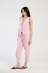 Modella indossa completo rosa: gilet senza maniche e pantaloni, stile romantico e trendy.