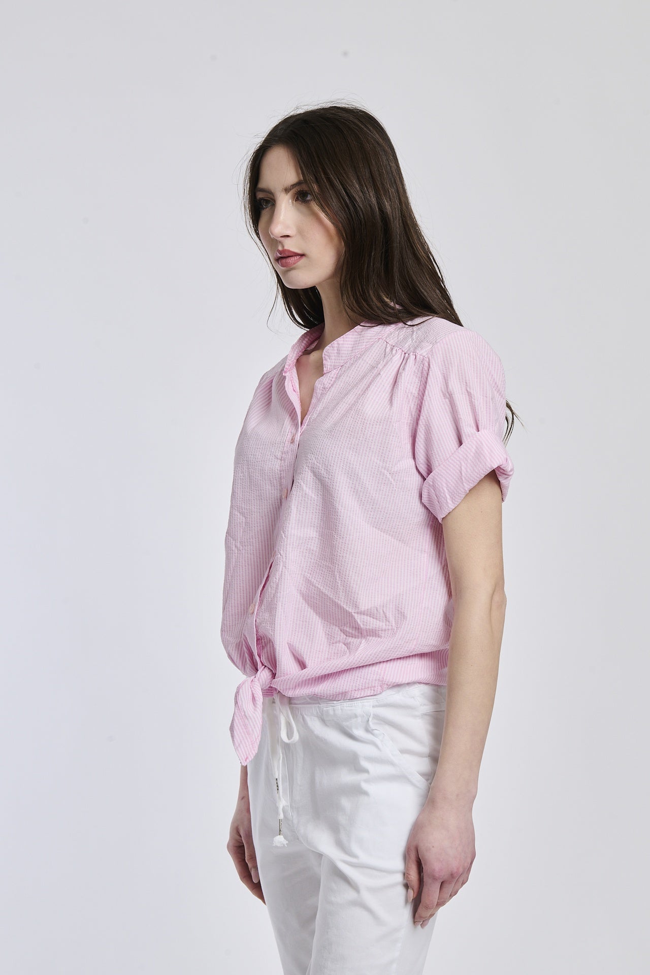 Camicia a righe rosa da donna, taglio oversize con nodo sul ventre, perfetta per un outfit casual e cool.