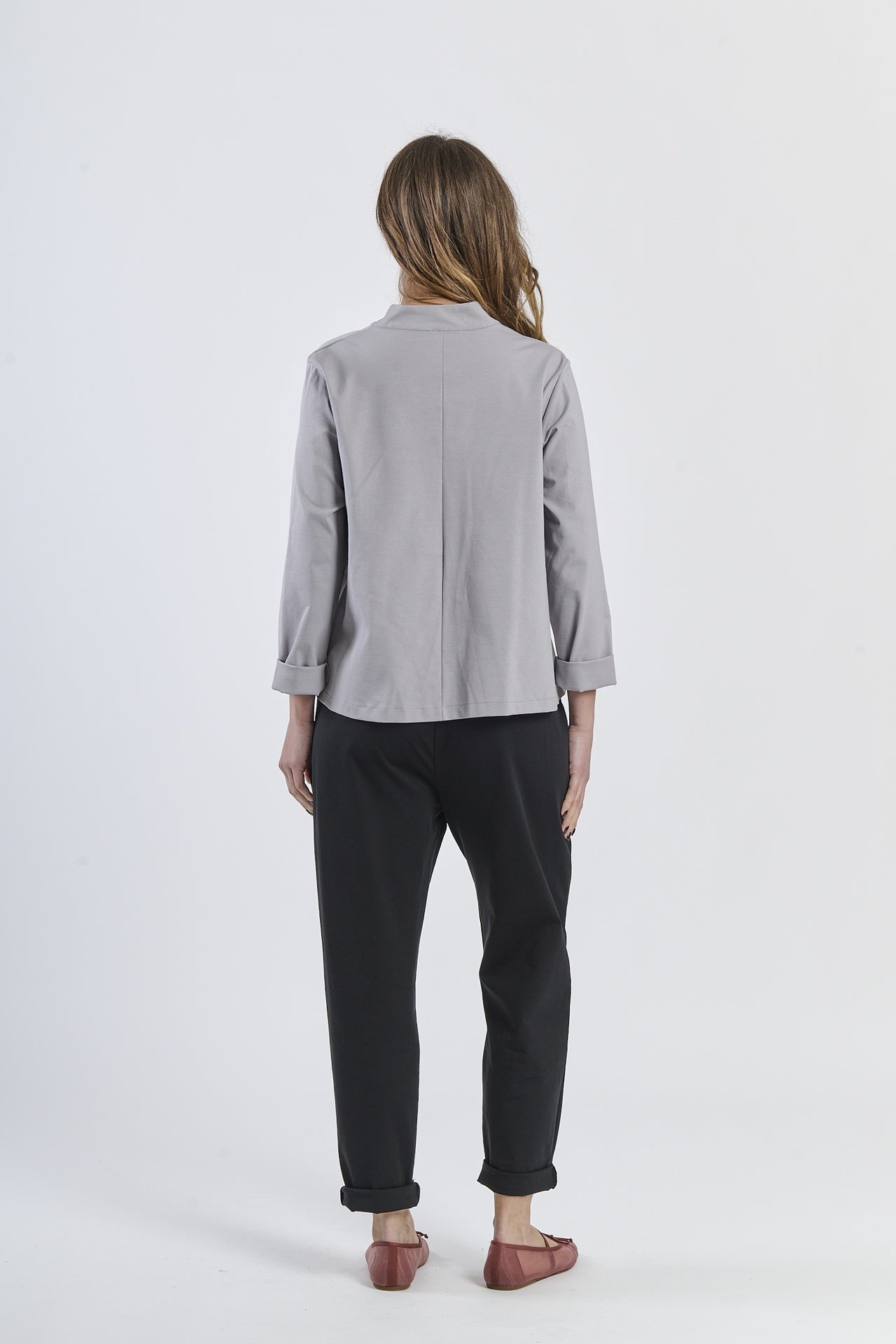 Combinazione di camicia grigio con apertura asimmetrica, pantaloni beige chiari e scarpe marroni, modernità minimal