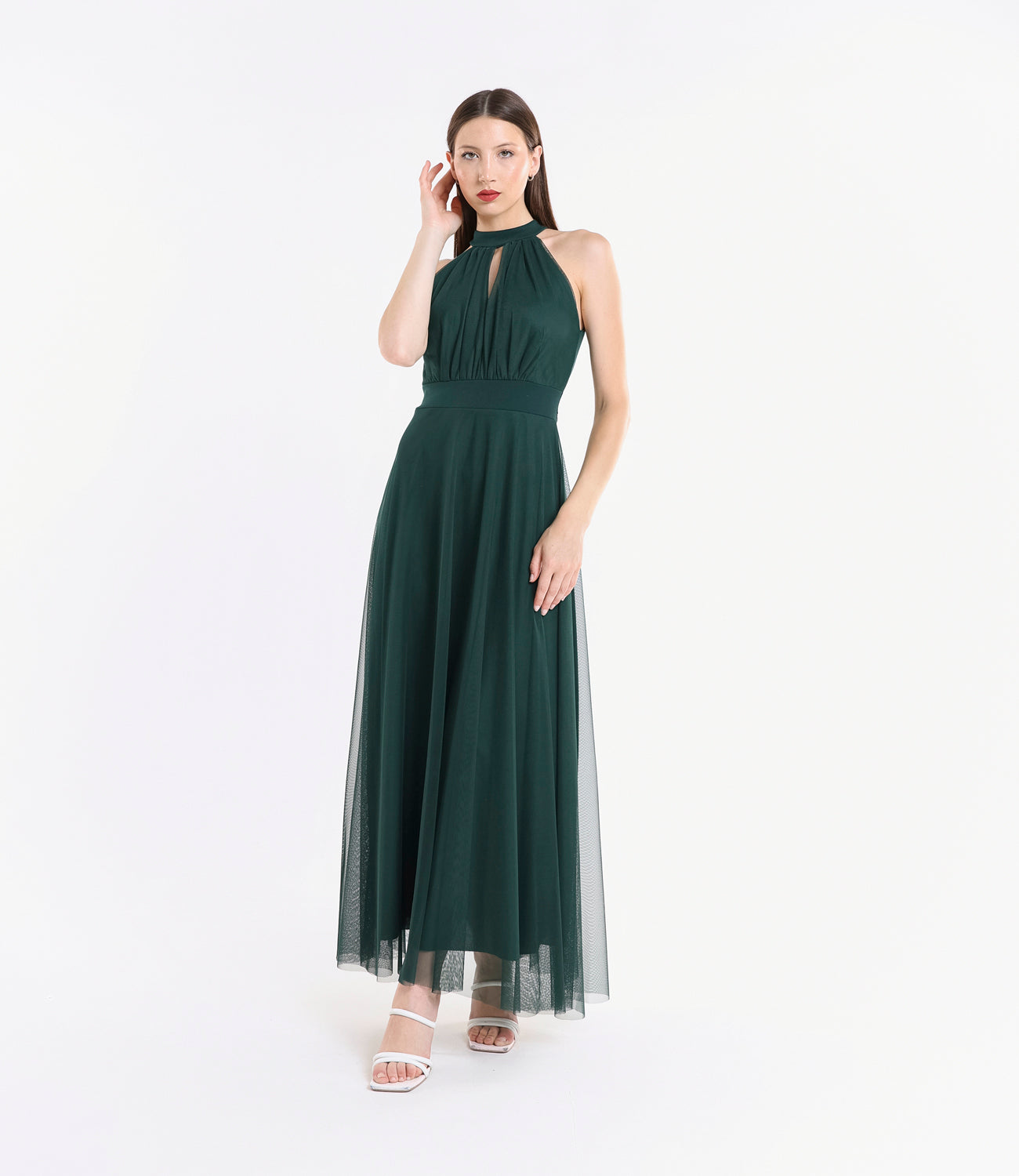 Donna con abito lungo verde.S, colletto a nodo, pianta verde tropicale accanto