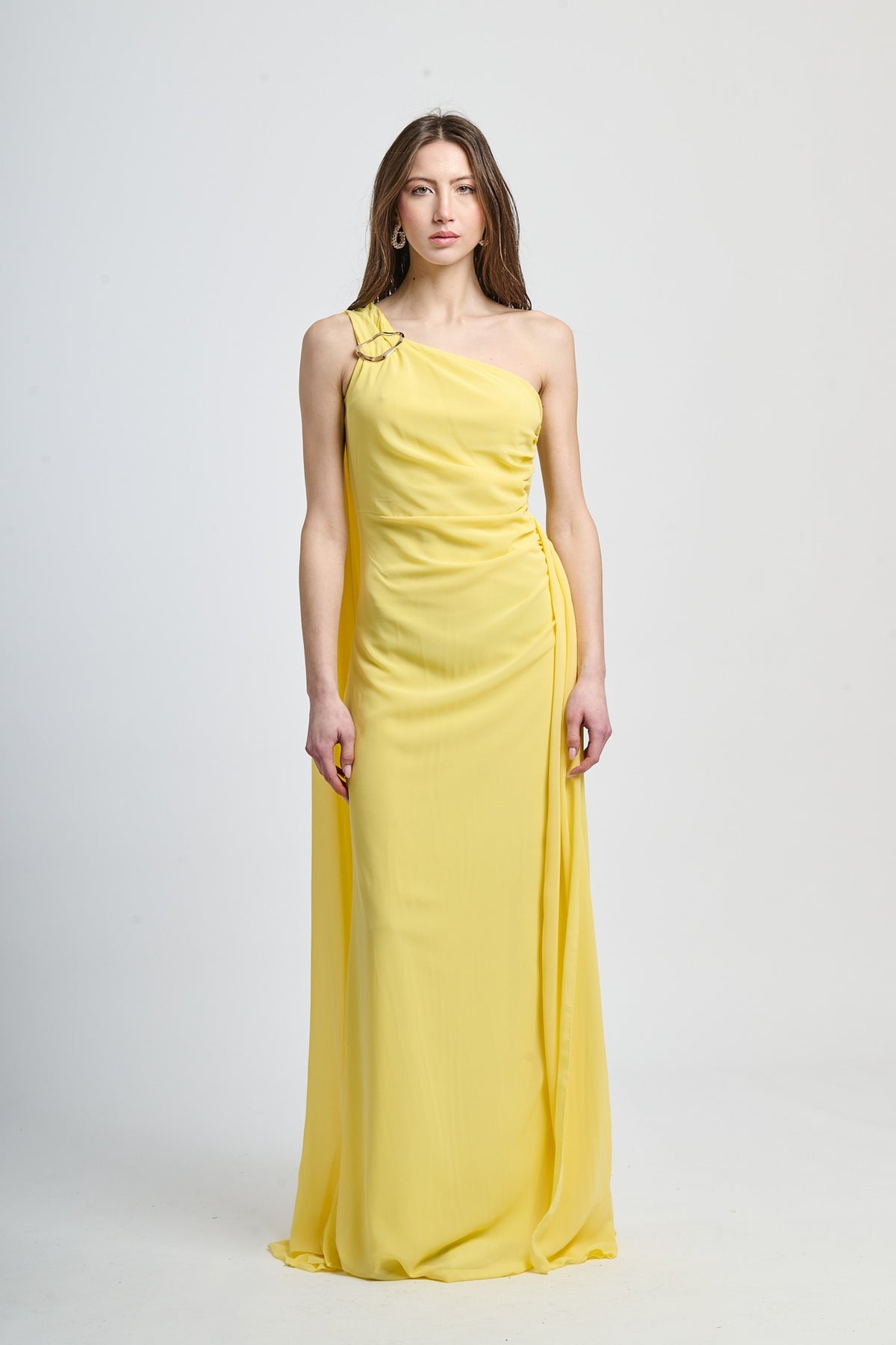 Abito lungo giallo, spalla singola, drappeggio fluido, accessorio decorativo sulla spalla.