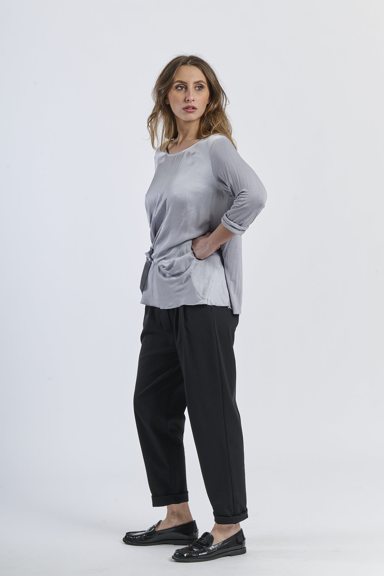 Blusa grigia a maniche 3/4, abbinata a pantaloni neri, armonia neutra