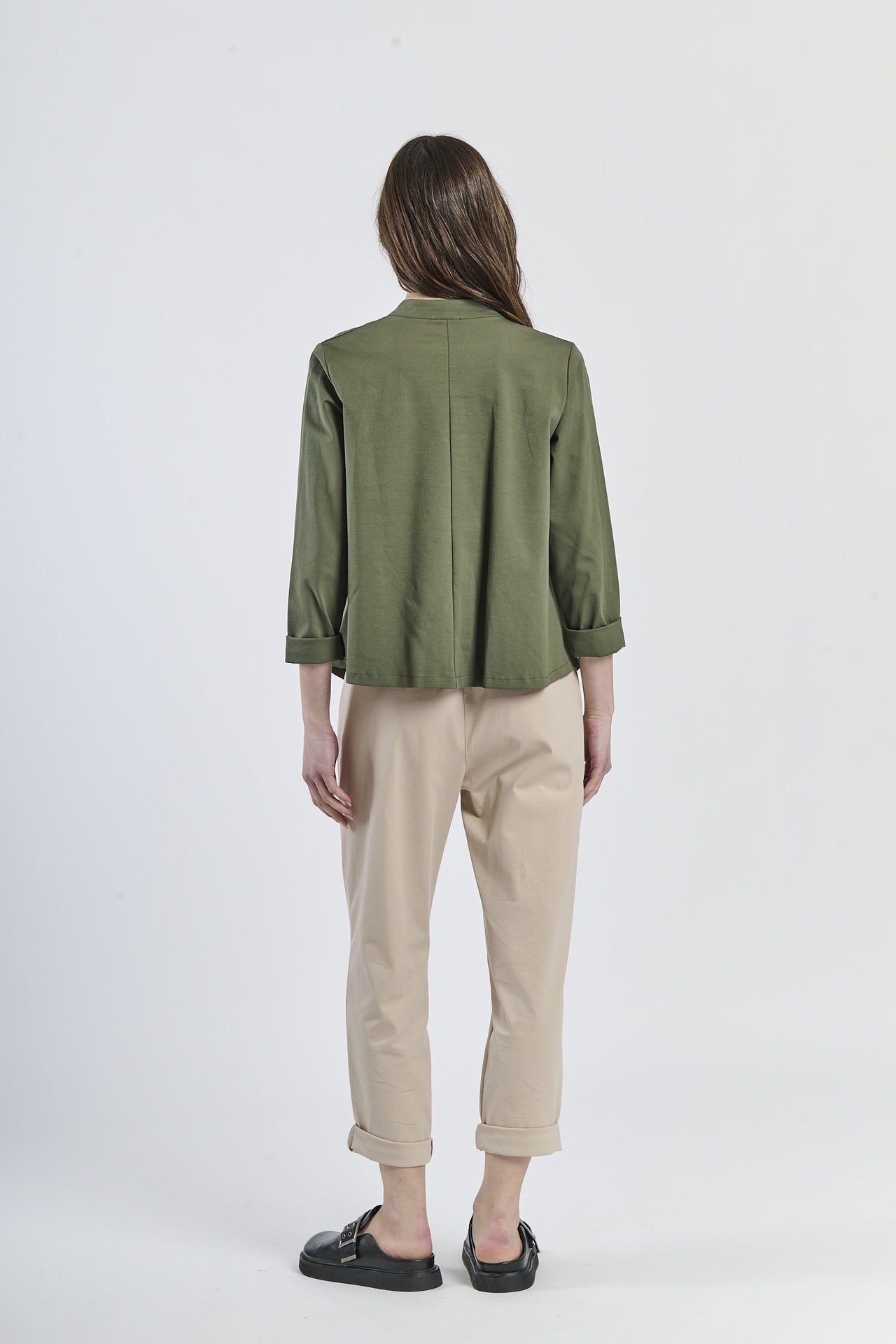 Combinazione di camicia oversize verde con bottoni laterali e pantaloni beige, stile casual-elegante