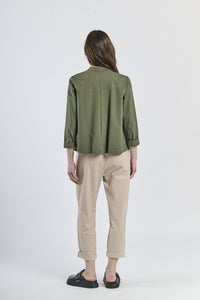 Combinazione di camicia oversize verde con bottoni laterali e pantaloni beige, stile casual-elegante