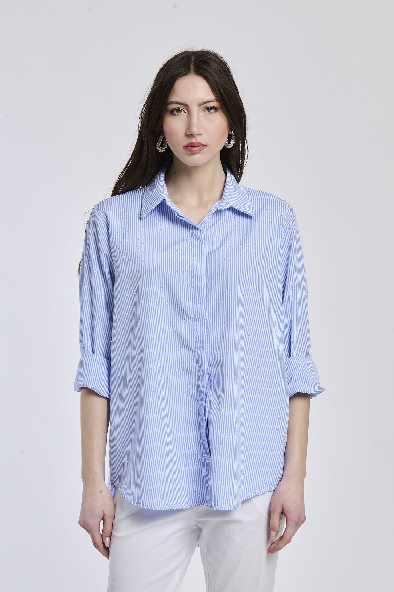 Donna indossa una camicia a righe blu , colletto a camicia, maniche 3/4, taglio ampio e versatile.
