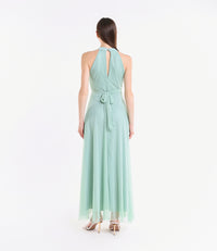 Abito salvia intenso, collo alto a nodo, pianta verde artificiale nel background