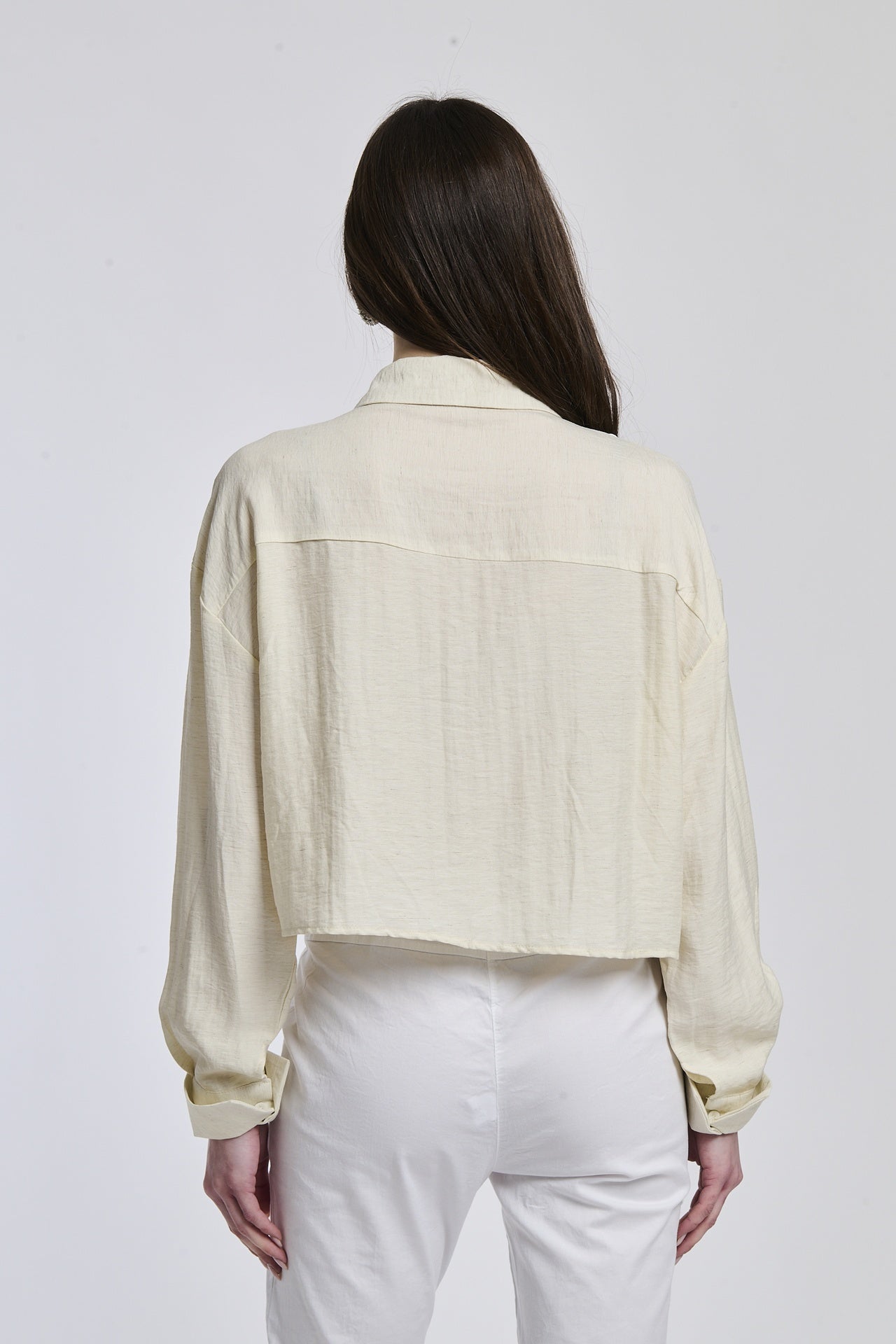 Donna veste una camicia a righe di un blu profondo e bianco, con un taglio leggermente oversize e maniche lunghe, che conferisce un senso di comfort e stile.