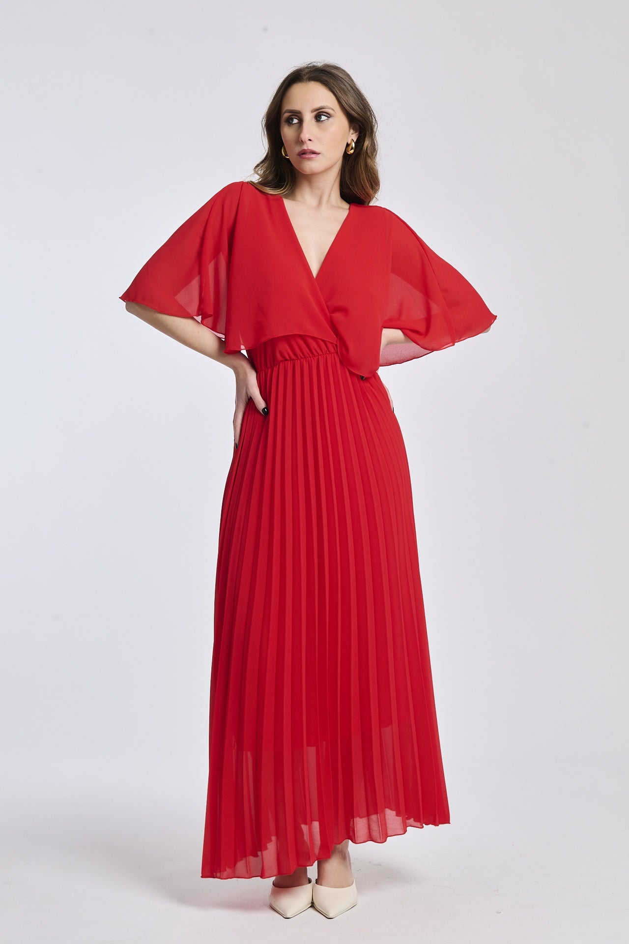 Un abito in rosso con lo stesso disegno crociato e maniche a mantello, creando un'atmosfera di intensità e fascino.