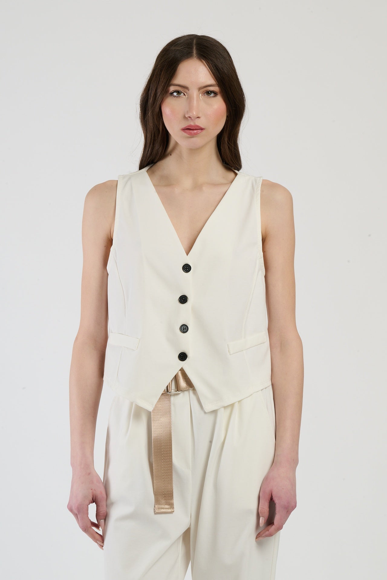 Donna con completo bianco: gilet e pantaloni, luminosità e freschezza per un look impeccabile.