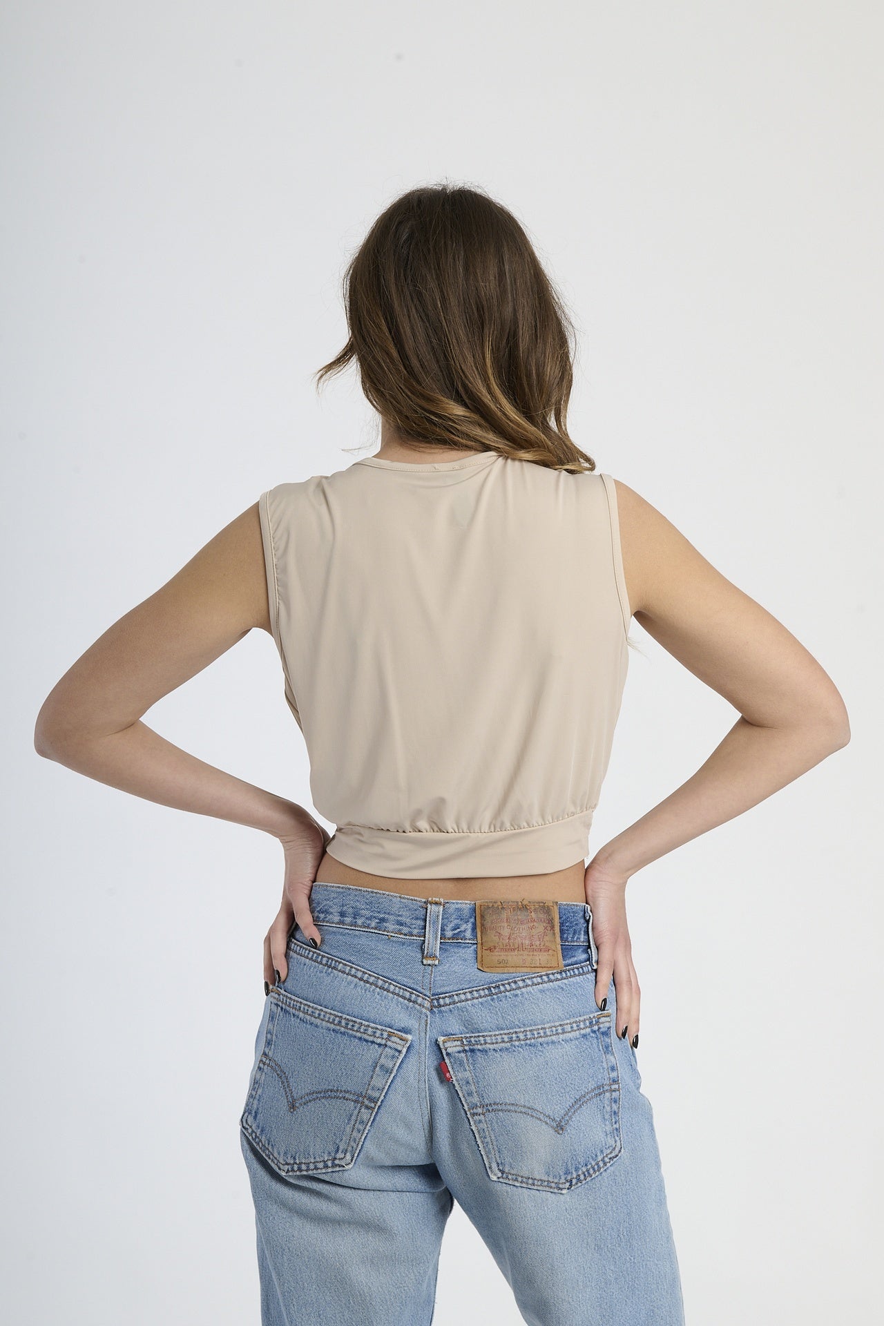 Canotta beige con scollatura a V, fibbia frontale e taglio cropped, ideale per un outfit neutro.