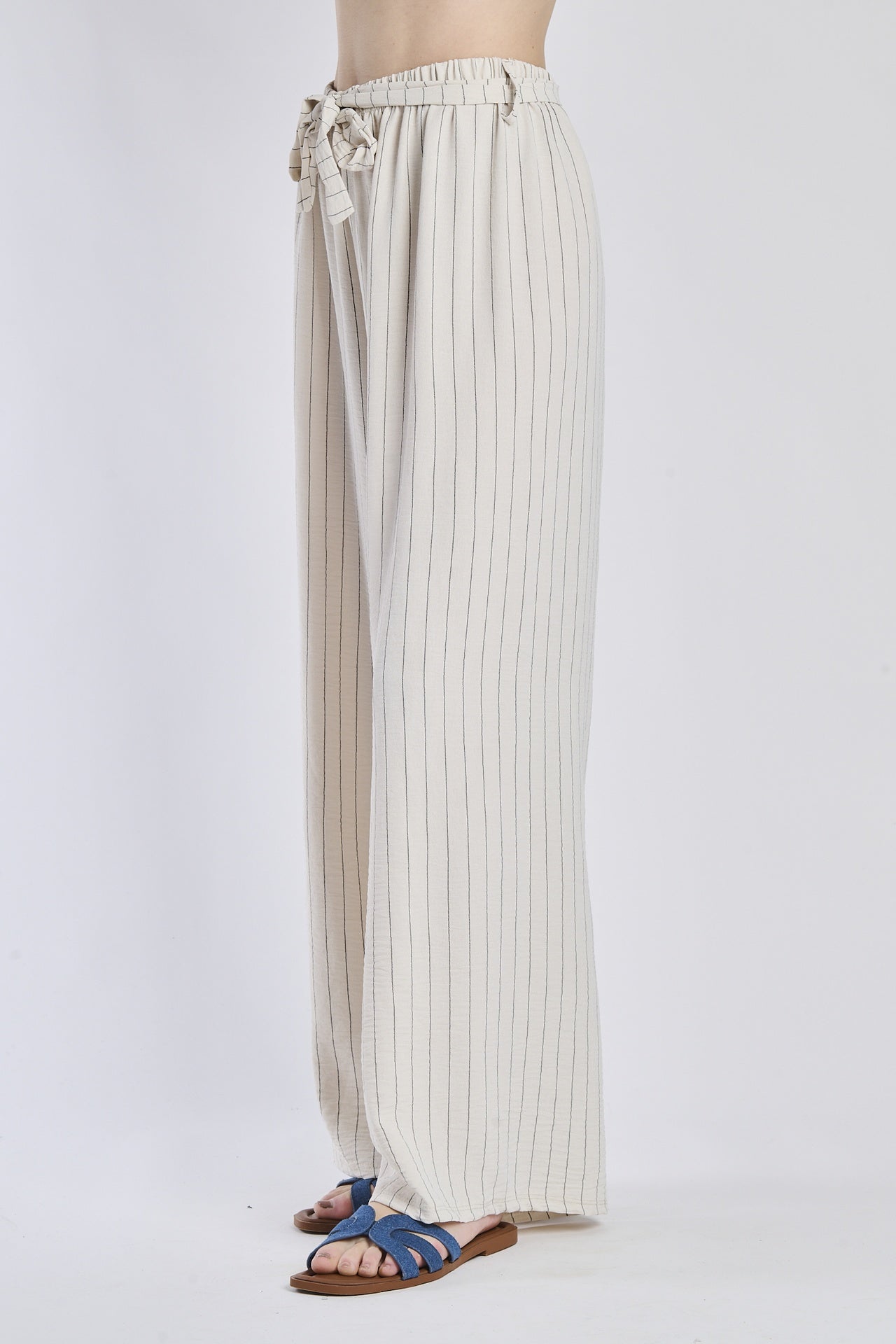 Pantaloni fluido beigi, taglio ampio, nodo decorativo in vita, adatti per l’outfit quotidiano.