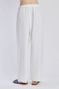 Pantaloni larghi bianchi con coulisse e nodo in vita, abbinati a sandali.