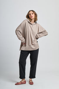 Outfit con felpa fango con cappuccio e pantaloni neri, contrasto caldo