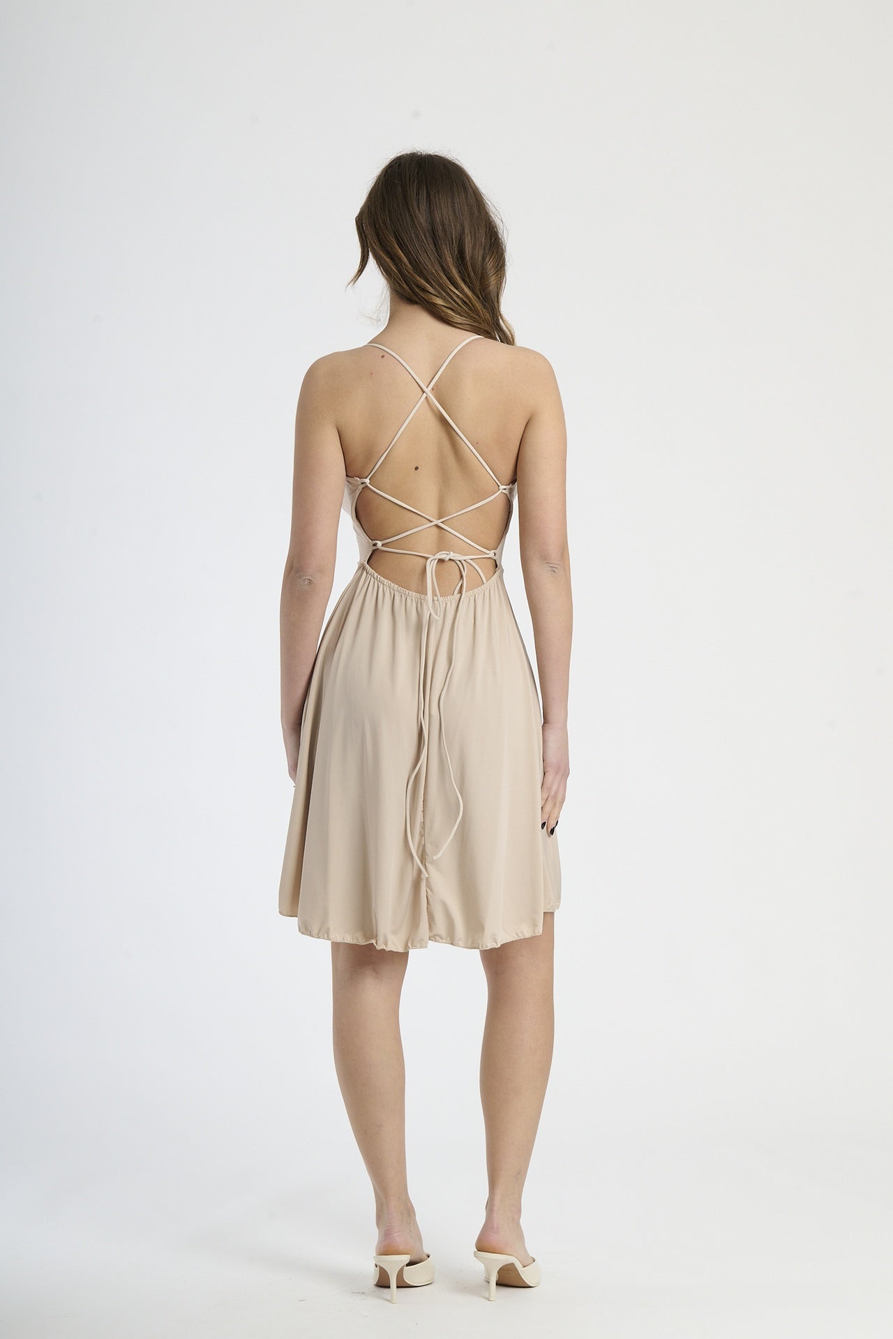 Vestito beige in tessuto morbido, silhouette a campana con bretelle sottili, ideale per giornate di sole.