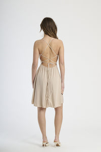 Vestito beige in tessuto morbido, silhouette a campana con bretelle sottili, ideale per giornate di sole.