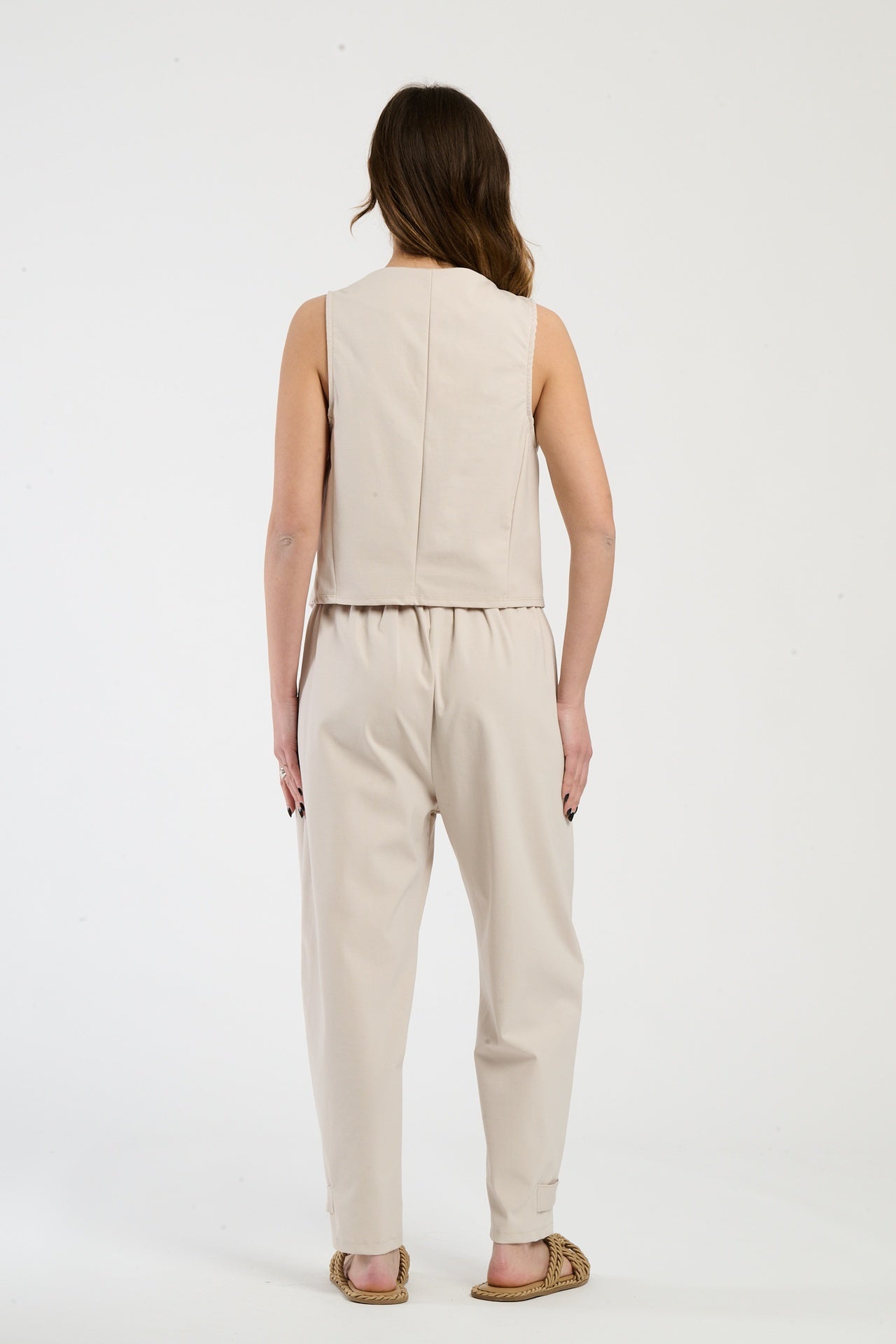 Modella indossa completo beige: gilet senza maniche