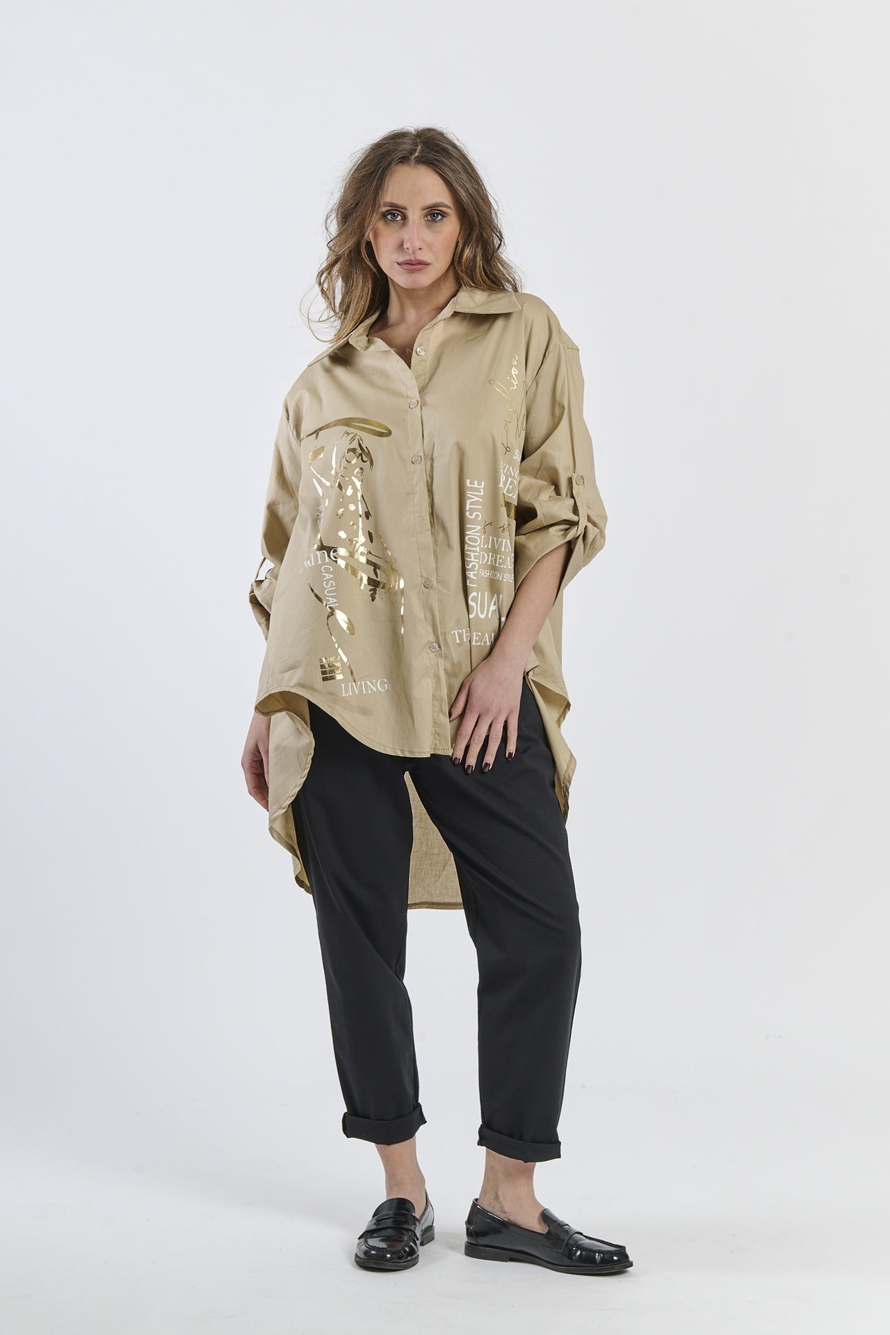 Camicia oversize beige con stampa dorata, abbinata a pantaloni neri