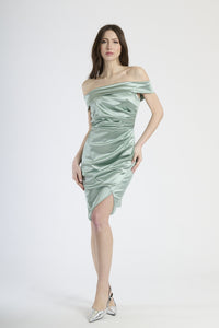 Donna con abito salvia a spalla nuda, tranquillità e eleganza soffusa.