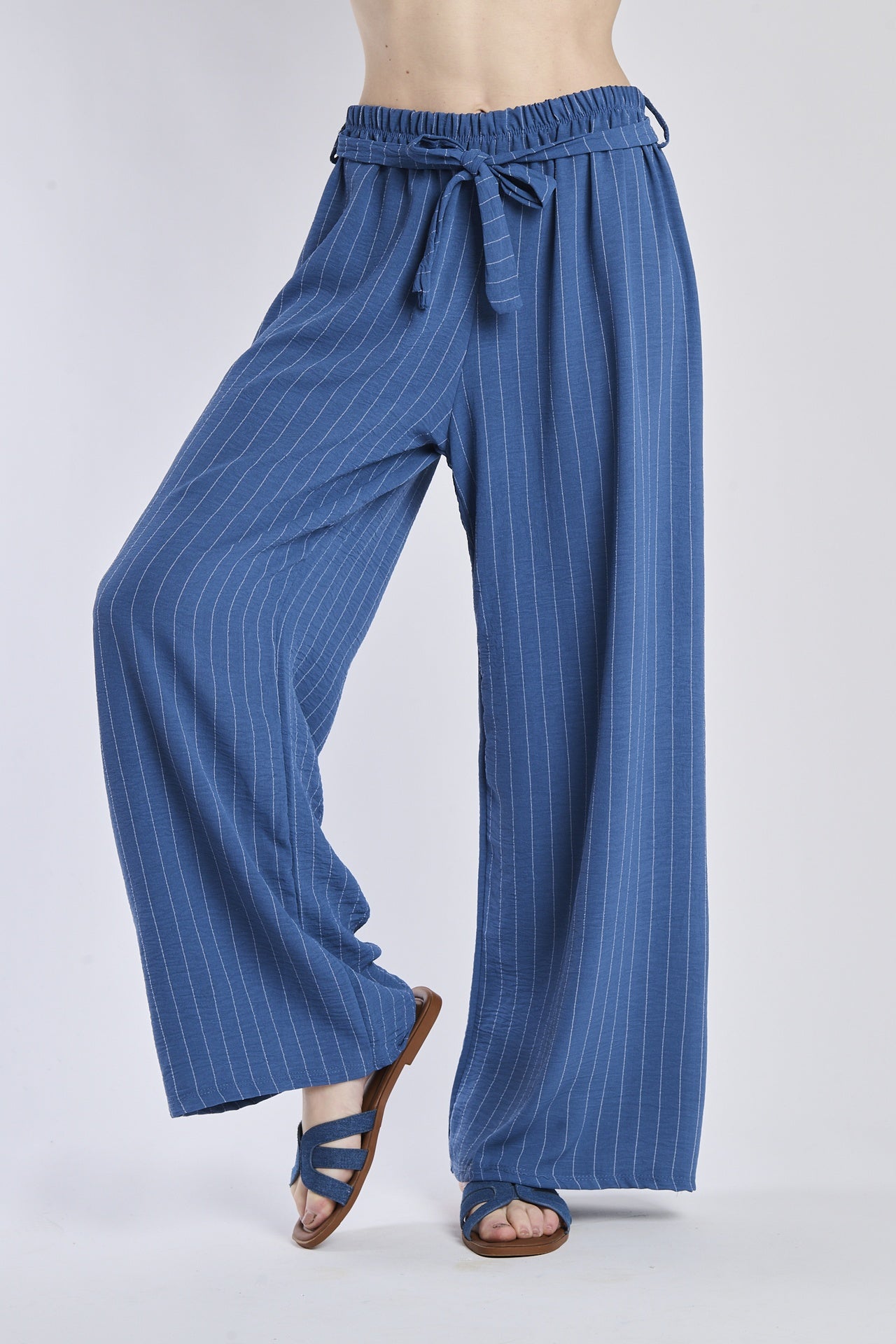 Pantaloni larghi in denim con coulisse e nodo in vita, abbinati a sandali.