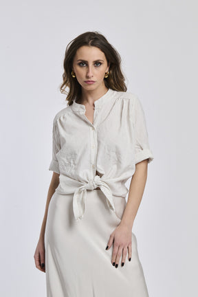 Camicia a righe beige e bianche da donna, nodo sul basso, abbinata a gonna beige, look 
