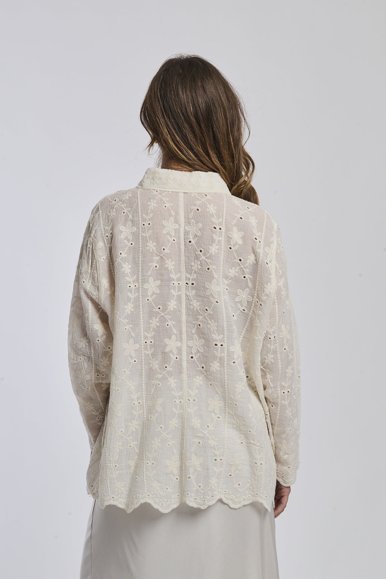 Camicia oversize beige con motivi floreali, abbinata a gonna bianca, posa semplificata