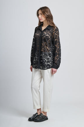 Camicia nera a fantasia, collo classico e maniche lunghe, abbinata a scarpe mocassini.