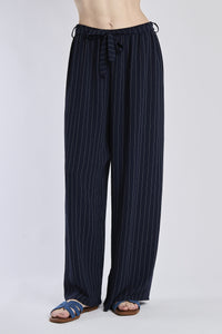 Pantaloni larghi navy con coulisse e nodo in vita, abbinati a sandali.