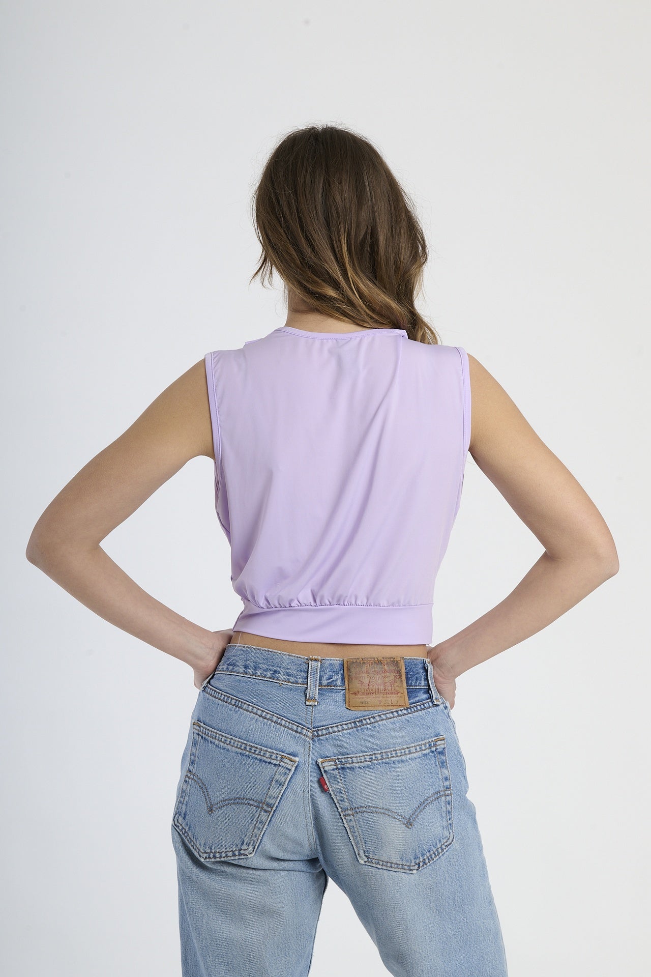 Maglia lilla senza maniche, design cropped con scollatura a V e fibbia decorativa.