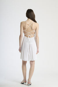 Vestito bianco in tessuto luminoso, silhouette a campana con bretelle sottili, ideale per eventi estivi e cerimonie leggere.