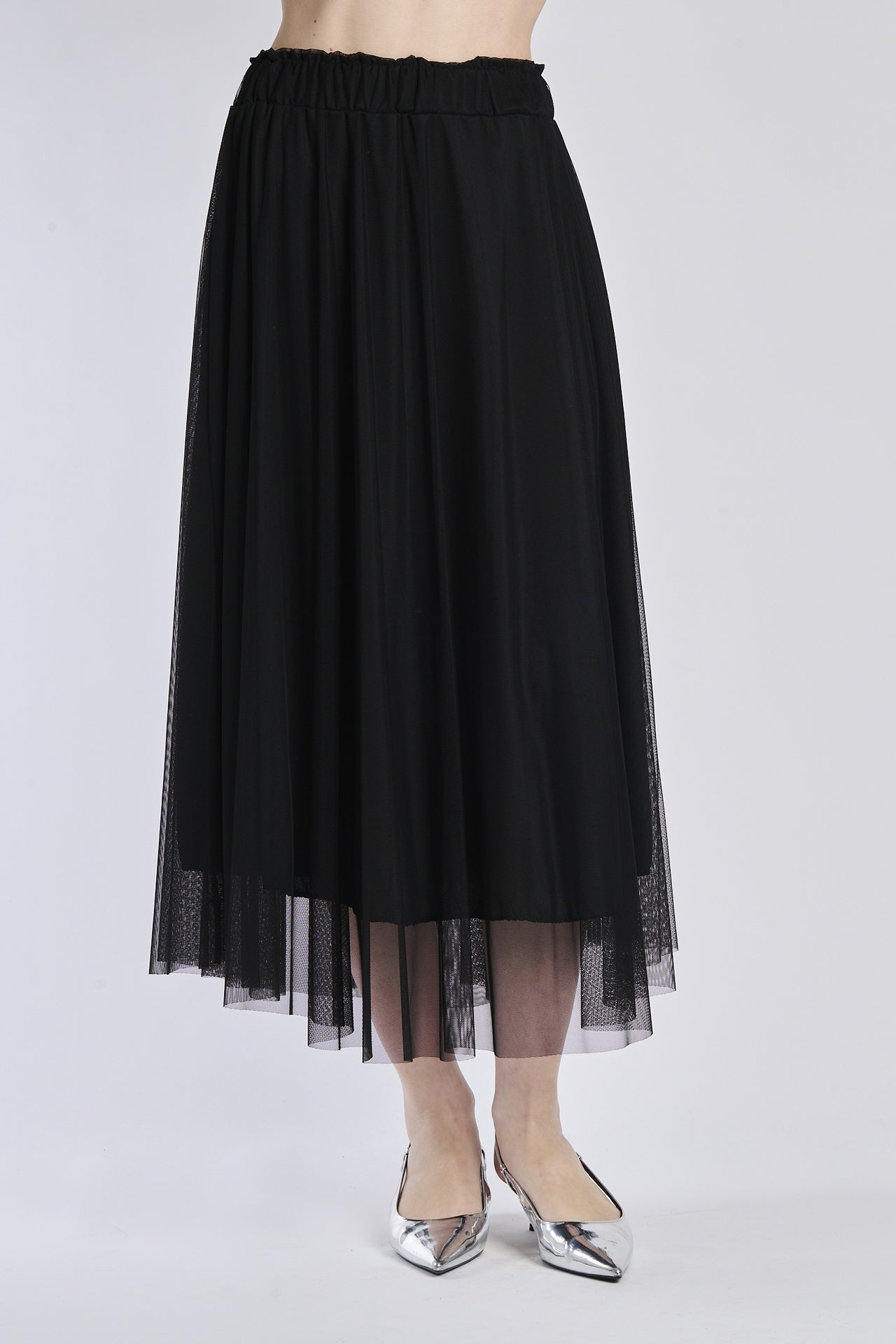 Gonna lunga in tulle nero, vita elastica, abbinata a sandali alti.