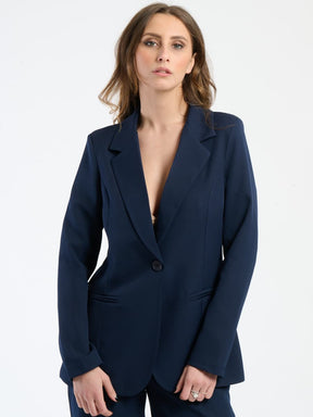 Outfit nero in tessuto lucido, blazer slim e pantaloni, ideale per un look serale.