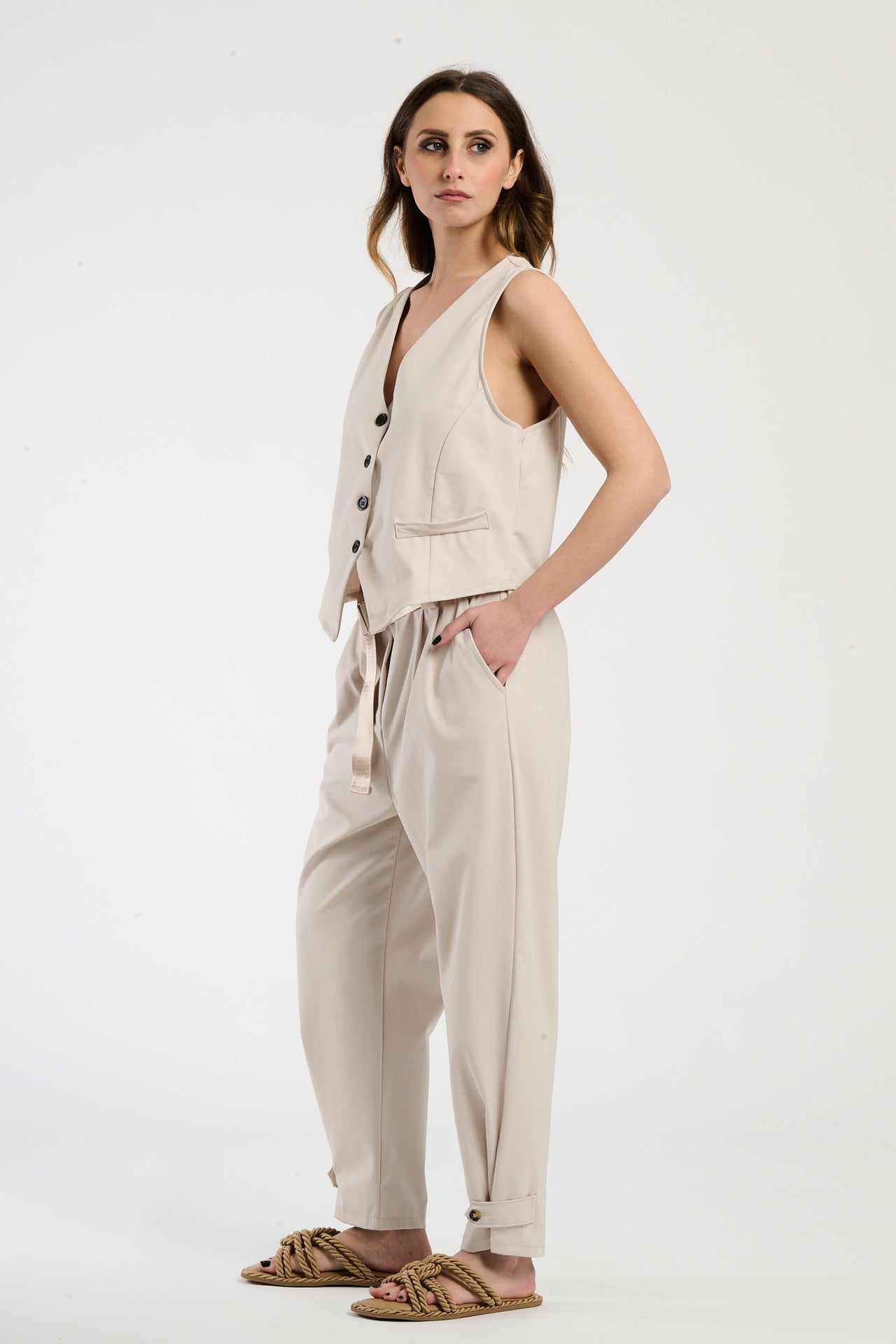Completo beige su una modella: gilet a bottoni e pantaloni, combinazione