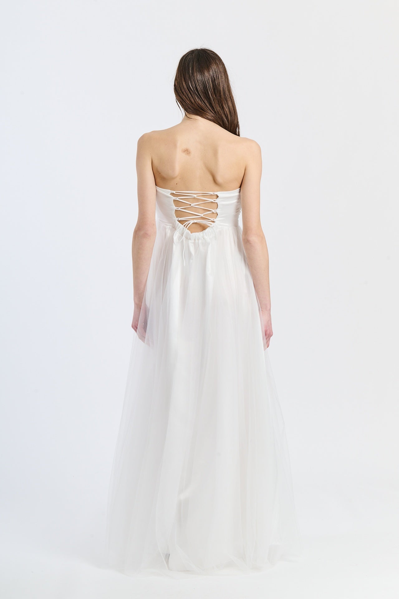 Abito da sposa bianco in tulle luminoso, scollo a barca e gonna fluida, ideale per occasioni eleganti e naturali
