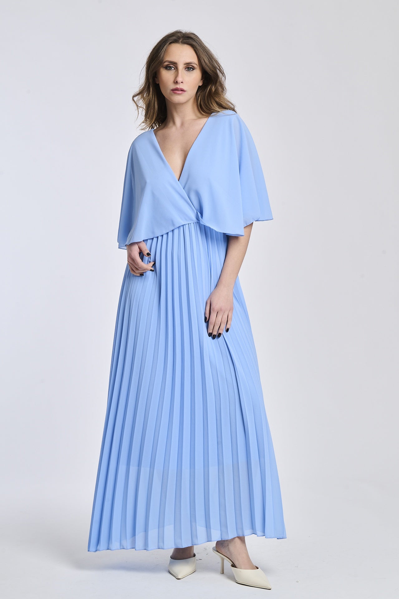 Vestito in azzuro chiaro con dettagli di maniche a mantello e falde, offrendo un'estetica contemporanea e sofisticata.