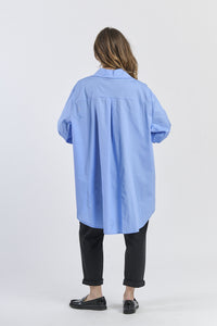 Outfit con camicia azzurra larga e pantaloni neri, contrasto interessante