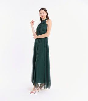 Abito verde.S in tulle, colletto alto, posa vivace accanto a pianta verde