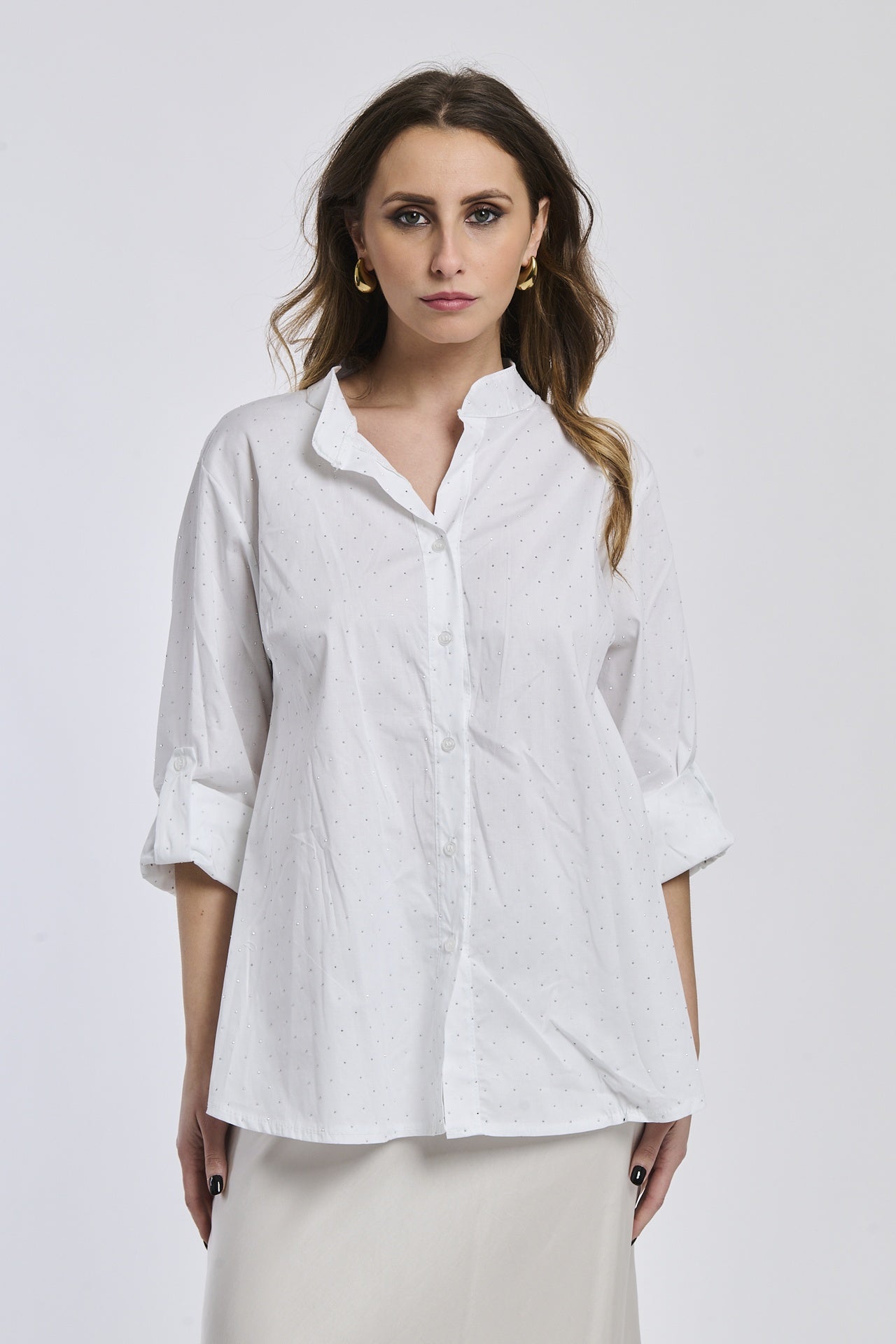 Donna con camicia bianca oversize, colletto coreano, bottoni frontali e maniche arrotolate a 3/4