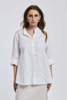 Donna con camicia bianca oversize, colletto coreano, bottoni frontali e maniche arrotolate a 3/4