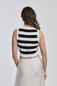 Maglia senza maniche a righe bianche e nere, taglio cropped, tricotata, collo tondo, abbinata a gonna bianca.