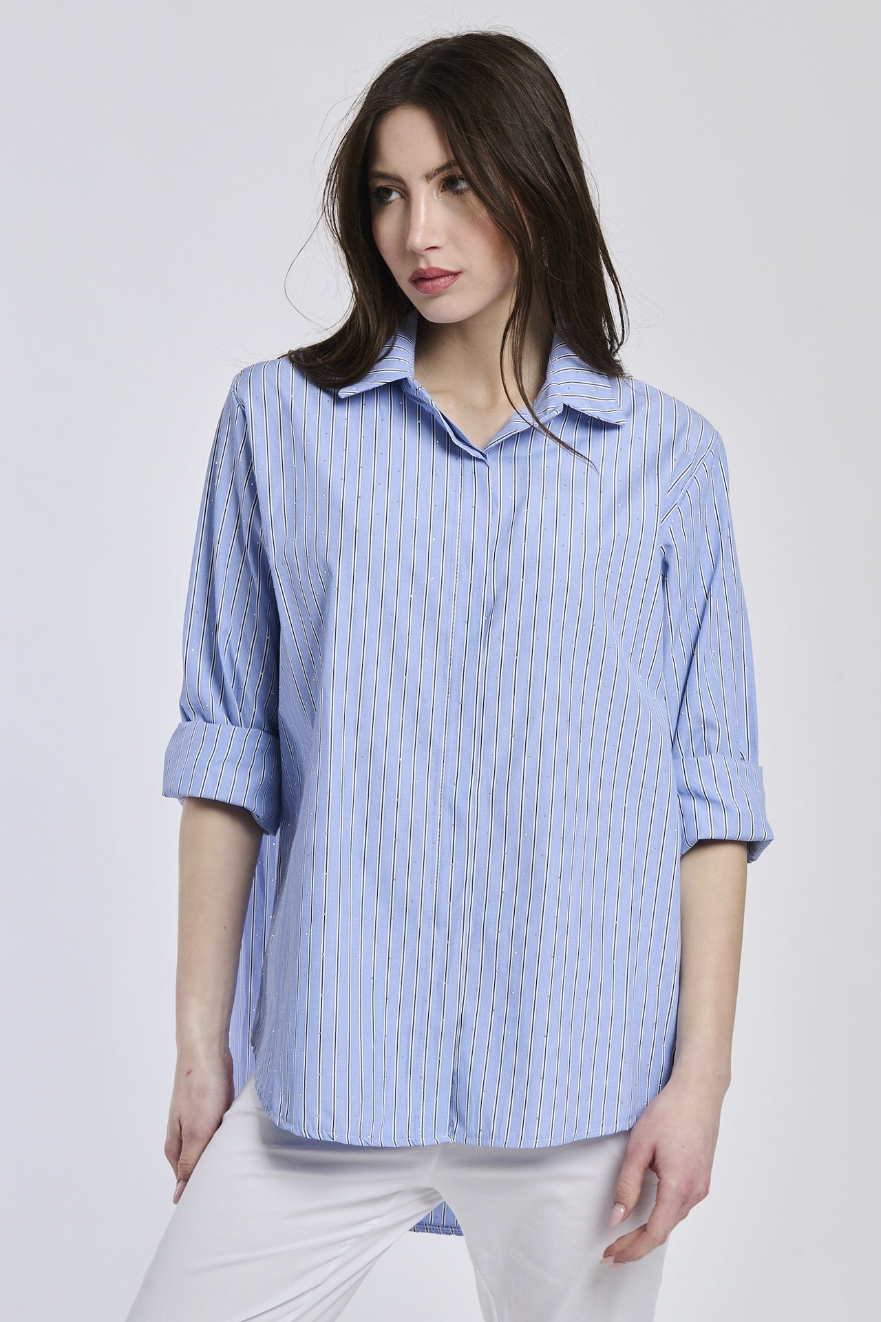 Donna indossa una camicia a righe blu e bianche, colletto a camicia, maniche 3/4, taglio ampio e versatile.