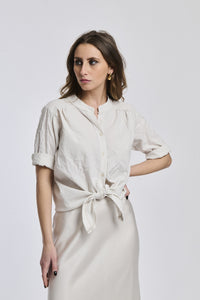 Camicia a righe beige e bianche da donna, nodo sul petto, che aggiunge un tocco di romanticismo.