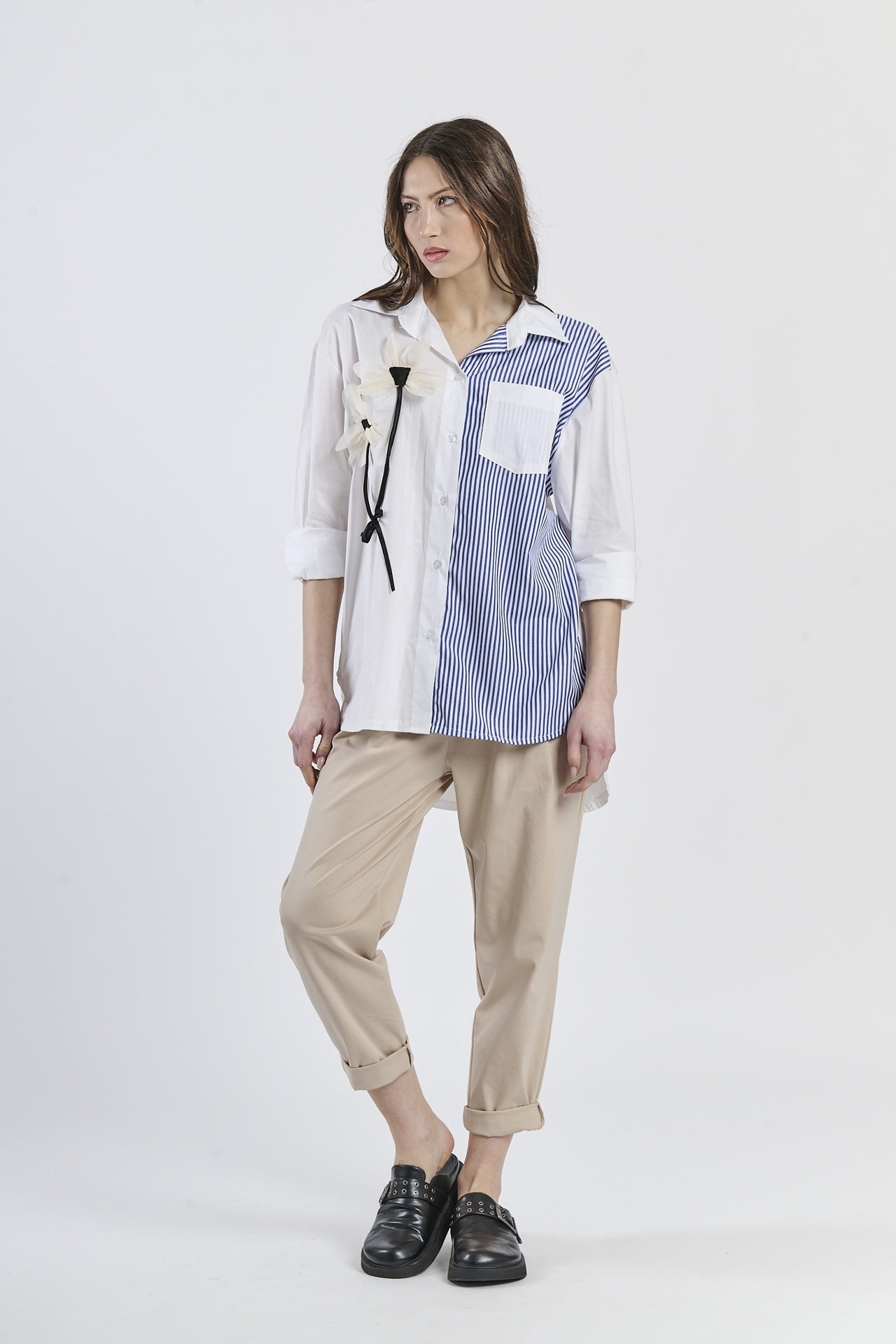 Camicia oversize bicolor navy e rosa a righe, con fiore decorativo e tasca contrastante, abbinata a pantaloni scuri e mocassini rossi