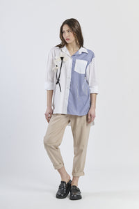 Camicia oversize bicolor navy e rosa a righe, con fiore decorativo e tasca contrastante, abbinata a pantaloni scuri e mocassini rossi