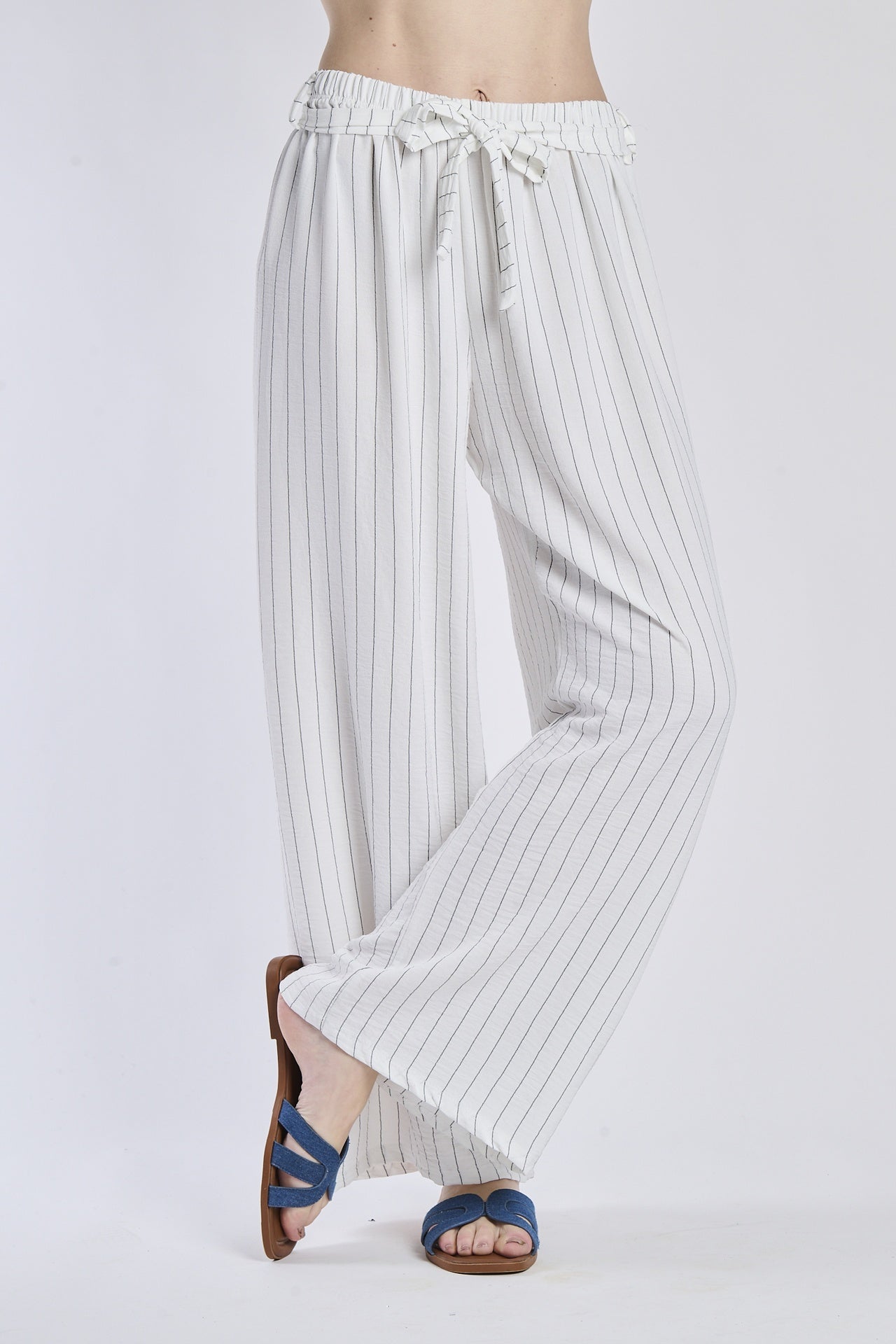 Pantaloni fluido bianchi, taglio ampio, nodo decorativo in vita, perfetti per la stagione estiva.