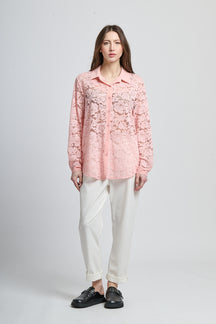 Camicetta rosa con motivi, collo camiciera e maniche lunghe, abbinata a pantaloni neri.