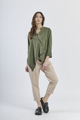 Outfit con camicia verde asimmetrica e pantaloni beige chiari, scarpe mocassini scure